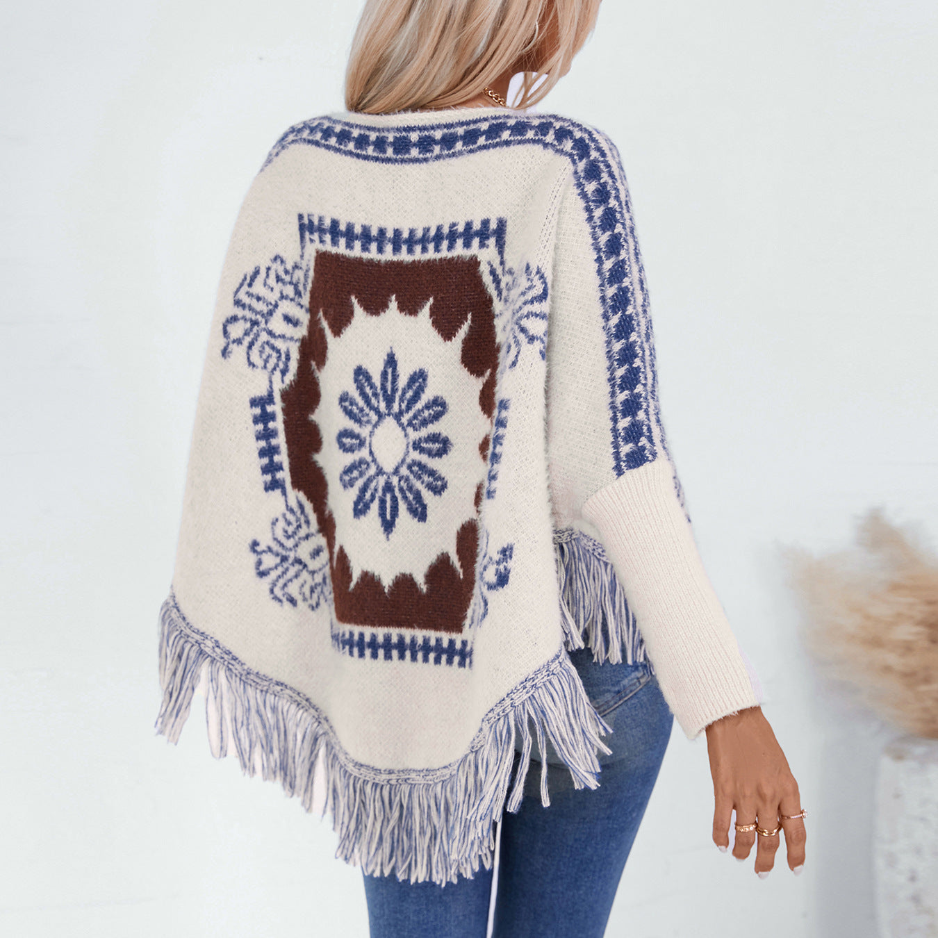 Ladies elegant knitted poncho with artistic pattern and fringed hem