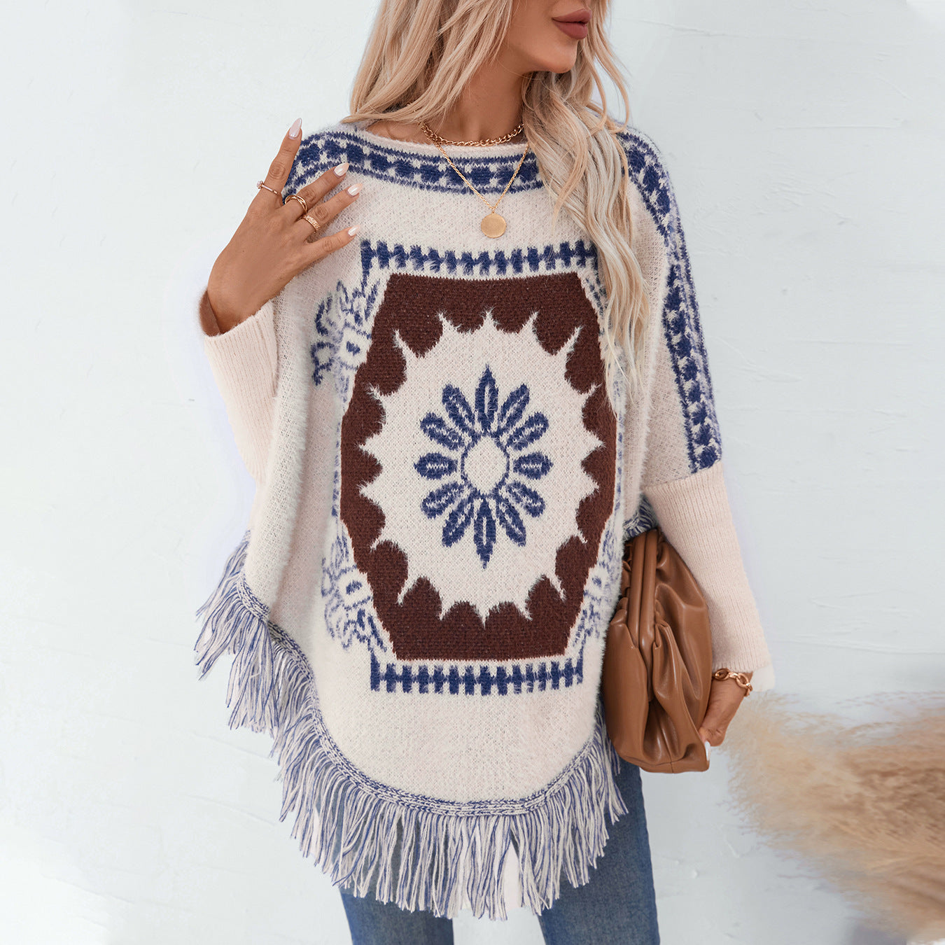 Ladies elegant knitted poncho with artistic pattern and fringed hem